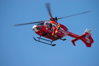 Low angle view of helicopter against clear blue sky