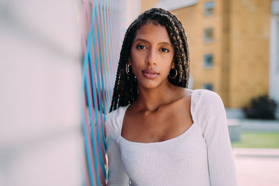 Portrait of smiling young woman leaning on wall