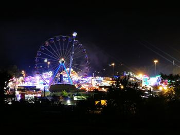 Illuminated ferris wheel against clear sky at night