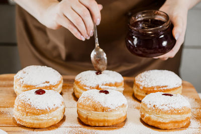Woman chef prepares fresh donuts with jam at her bakery. cooking traditional hanukkah sufganiyot. 