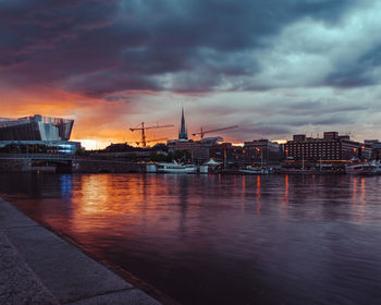 View of river and buildings against sky at sunset