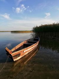 Boat moored on lake against sky