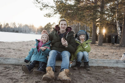 Father and his kids eating hot dogs at the beach together in winter