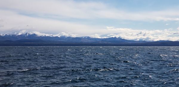 Scenic view of sea and snowcapped mountains against sky