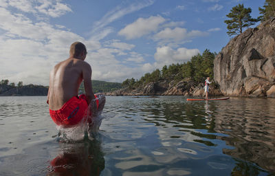 Rear view of shirtless man standing in water