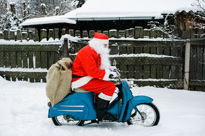 Man dressed in santa claus costume riding motorcycle on snow