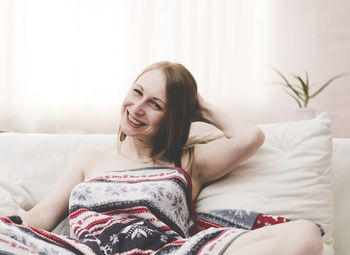 Portrait of young woman sitting on sofa at home