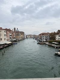 Buildings by river against sky