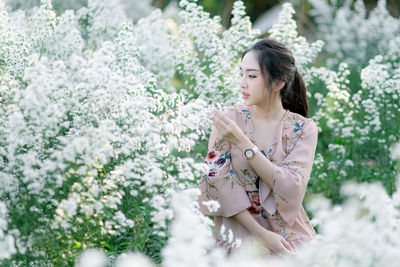 Woman sitting amidst white flowering plants