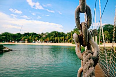 Close-up of metal chain on lake against sky