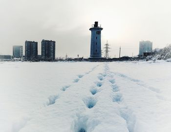 Snow covered buildings on field against sky