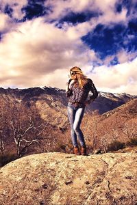 Man standing on mountain against cloudy sky