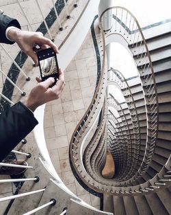 Cropped hands photographing spiral staircases using phone