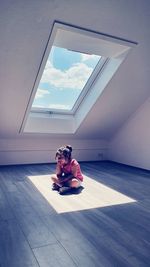 Full length of girl sitting on floor by window