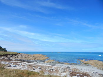 Rocks at beach against blue sky