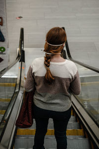 Rear view of woman standing on escalator