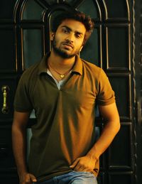 Portrait of young man standing against closed door