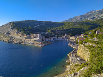 High angle view of townscape by sea against blue sky