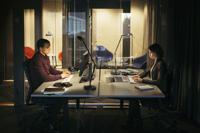 Side view of business colleagues working at desk in dark office