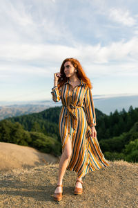 Portrait of woman standing by tree against sky