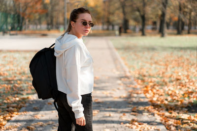 Side view of woman standing by tree during autumn