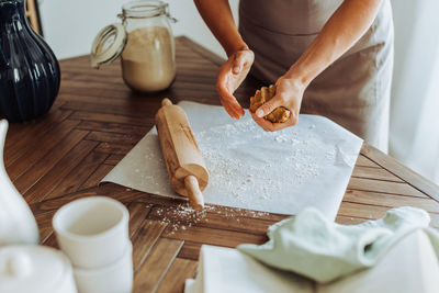 Woman preparing dough for rolling, rolling pin, flour, table top view