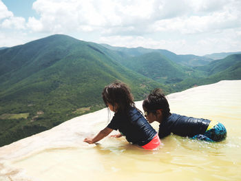High angle view of children enjoying in stream against mountains at hierve el agua