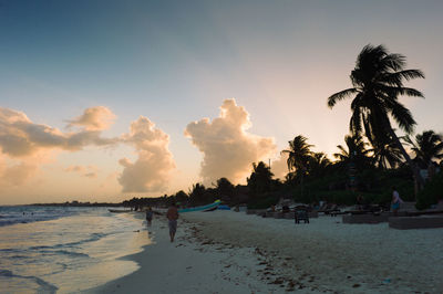 People on beach against sky during sunset