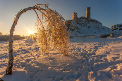 Snow covered land against sky during sunset