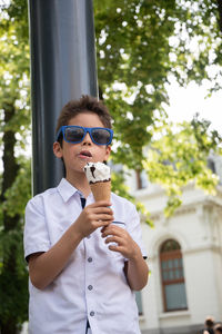 Cute child boy with a dirty face eats ice cream, the child enjoys dessert