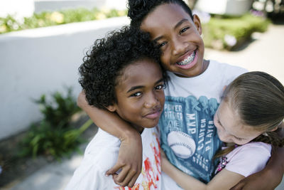 Portrait of brothers with sister standing on footpath in city