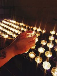 Close-up of hand holding lit tea light candles