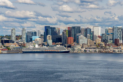 A cruise ship is docked in front of the seattle skyline.