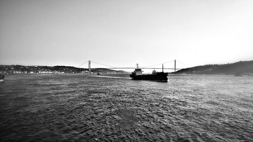 View of suspension bridge over sea against clear sky