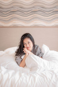 Portrait of young woman lying on bed at home