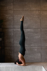Young sporty attractive woman practicing yoga doing headstand exercise
