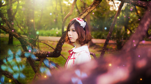 Portrait of young woman looking at tree