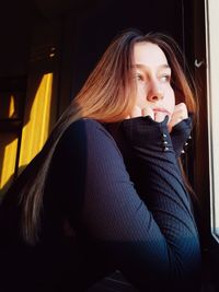 Young woman looking away while sitting at home