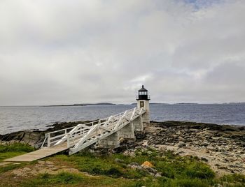 Lighthouse by sea against sky