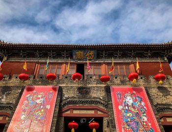 Low angle view of illuminated lanterns hanging by building against sky