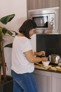Concentrated woman preparing breakfast with avocados, eggs and bread