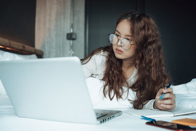 Young woman using phone while sitting on table