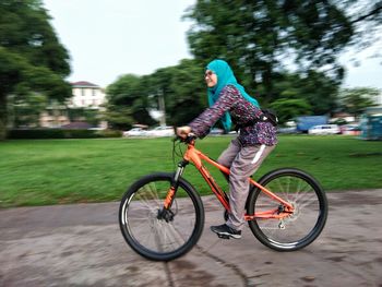 Side view of mid adult woman riding bicycle on street in city