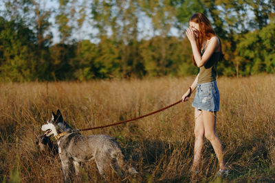 Side view of woman with dogs on field