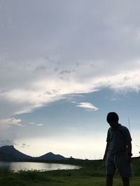 Rear view of man standing on mountain against sky