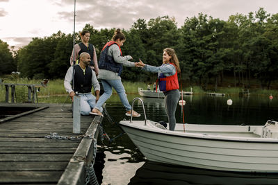 People on boat in lake against trees