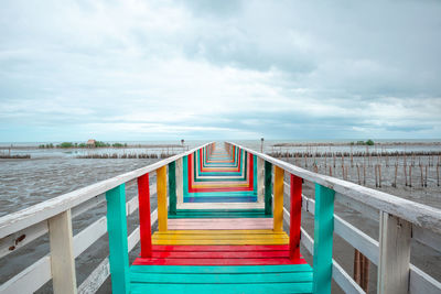 Footbridge over sea against sky