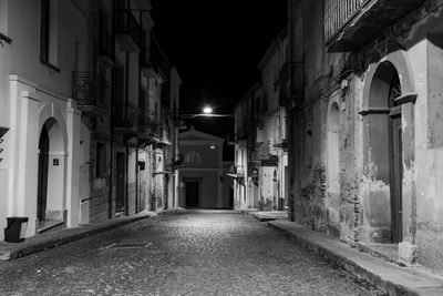 Narrow street amidst buildings at night