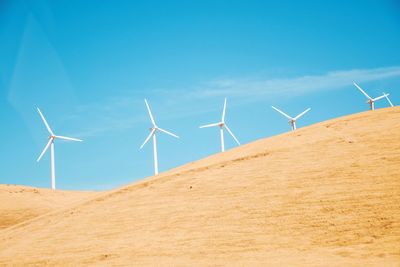 Wind turbines on desert against blue sky