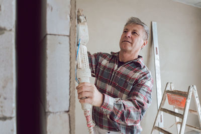 Portrait of man standing against wall at home